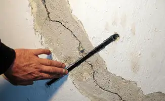 A wall with a large crack is being inspected by a professional in Sioux Falls, SD